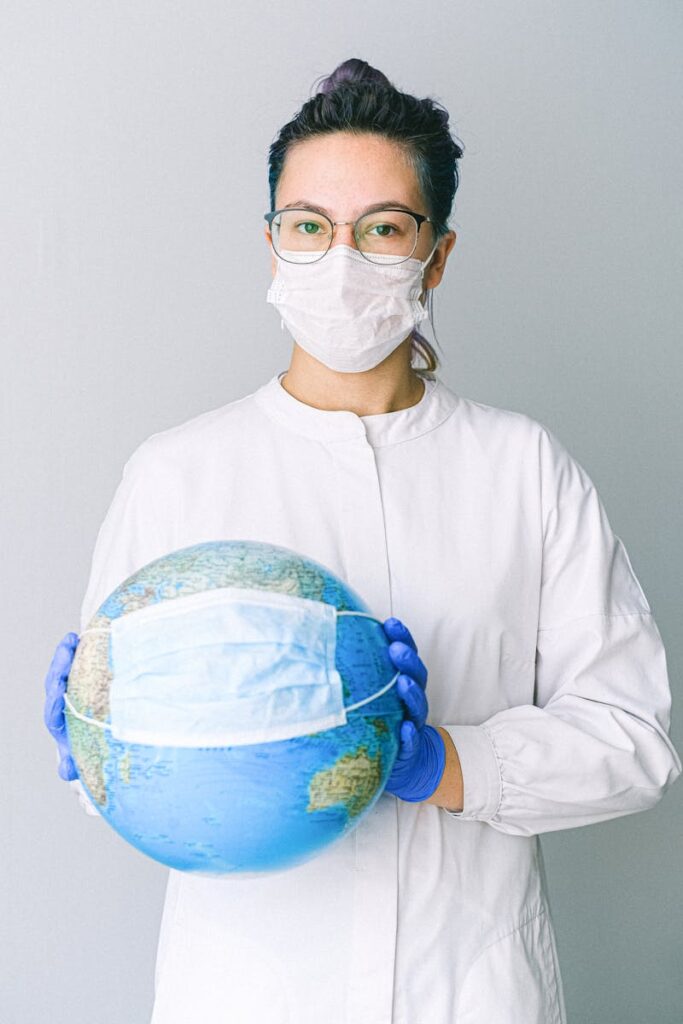 pexels-photo-4167541-4167541 Conceptual image of a doctor holding a globe with a mask, symbolizing global health.